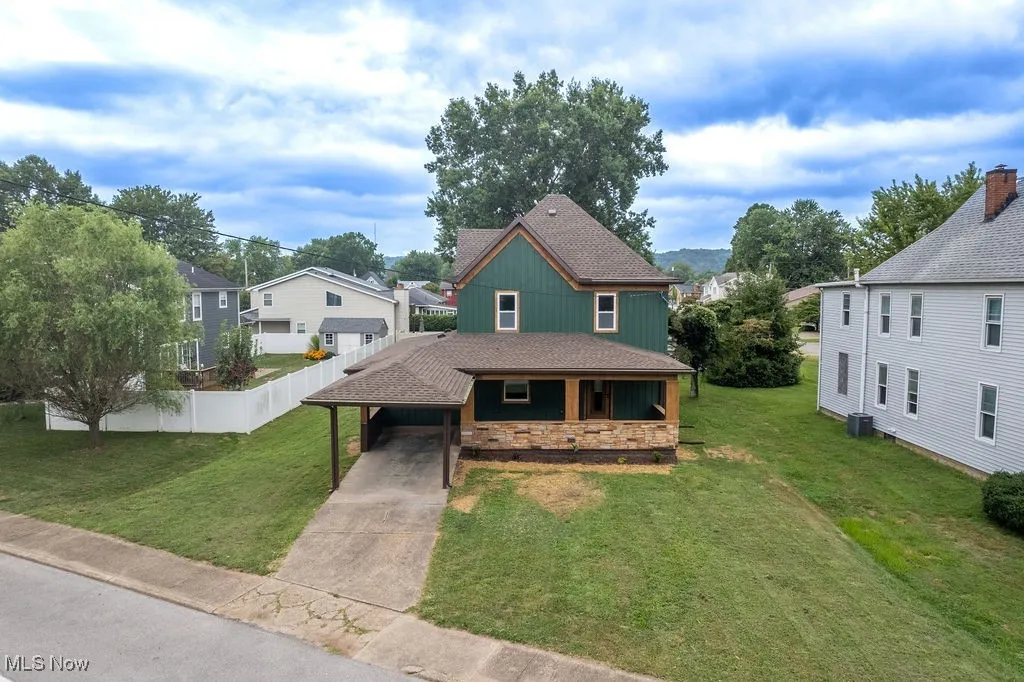 View of front of house featuring concrete driveway, a shingled roof, an attached carport, and stone siding