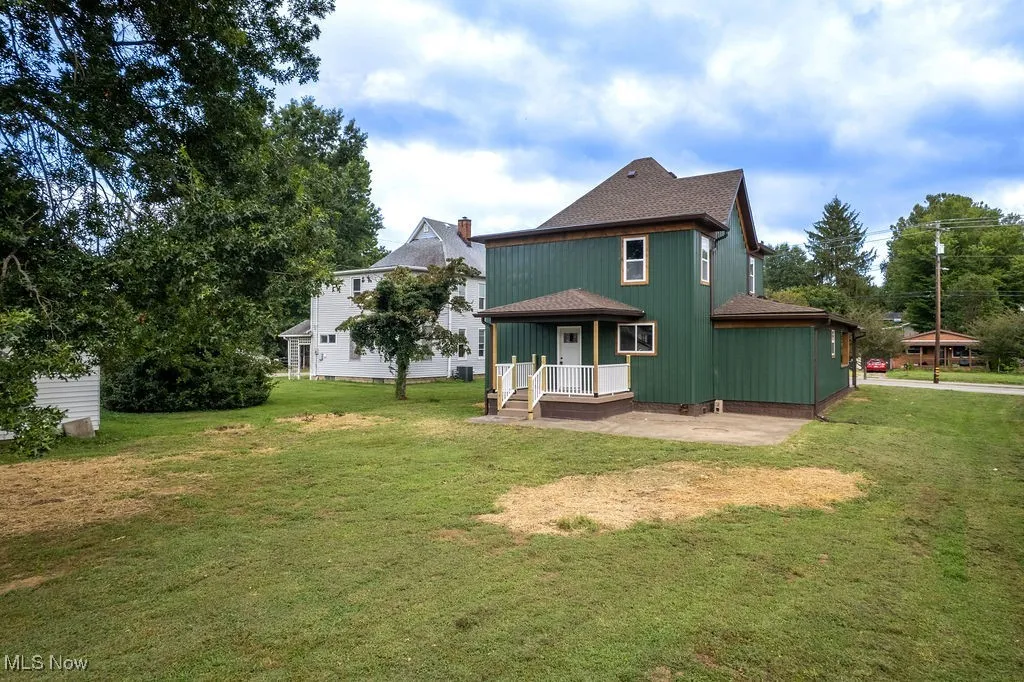 Back of house with a lawn, a patio, and roof with shingles