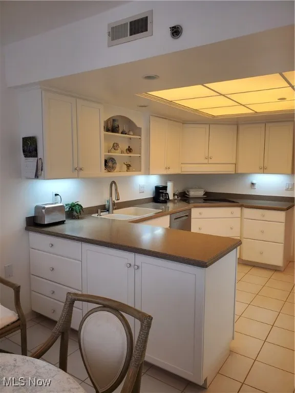 Kitchen with white cabinets, light tile patterned floors, open shelves, a peninsula, and dishwasher
