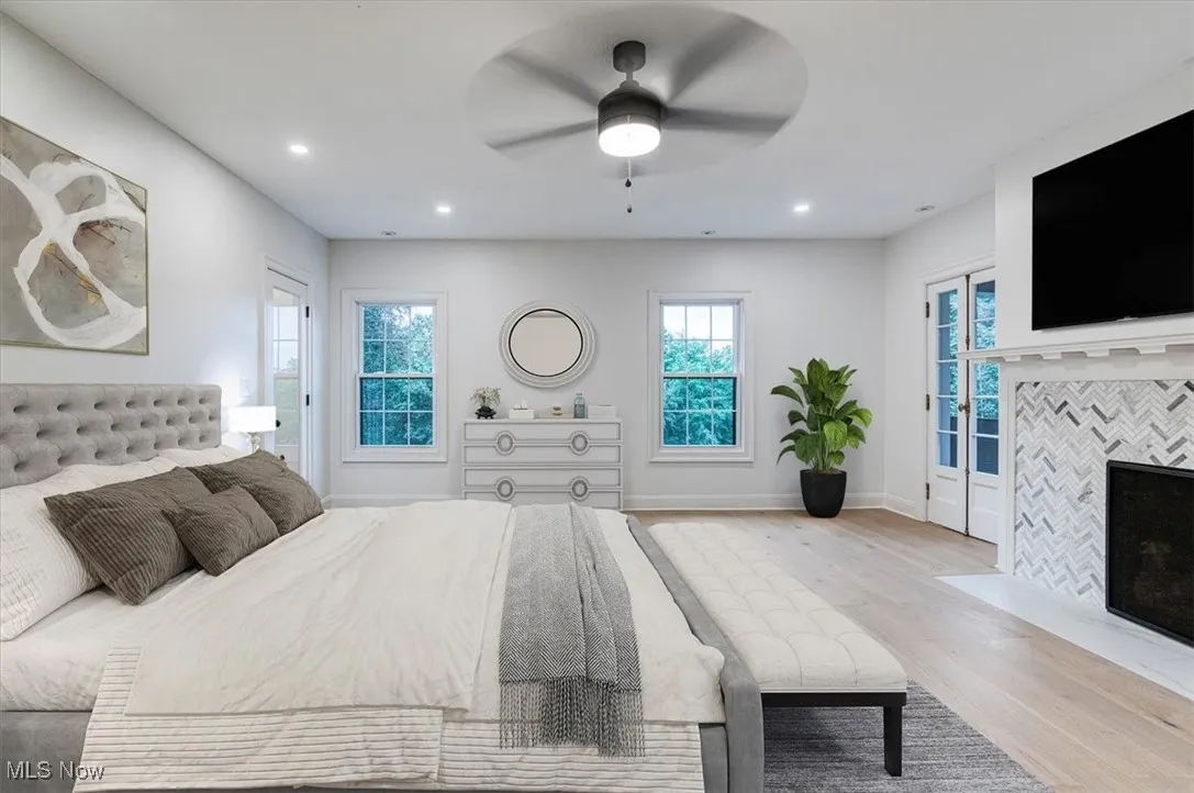 Bedroom featuring access to outside, light wood-type flooring, a ceiling fan, recessed lighting, and a tile fireplace