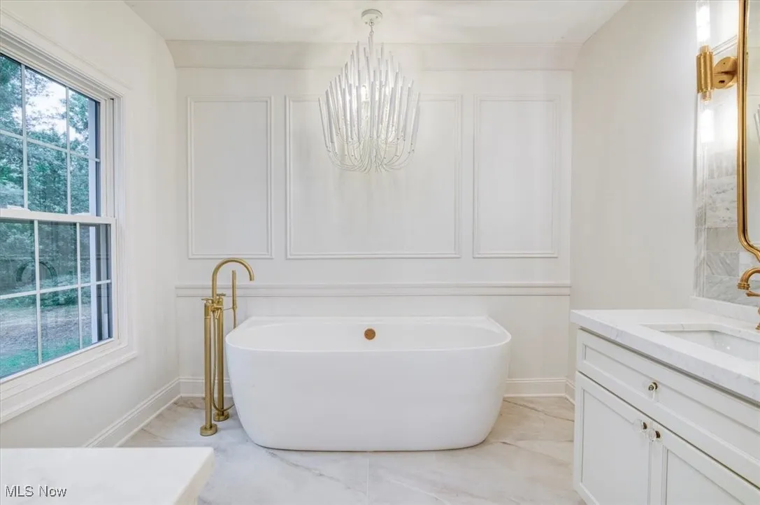 Full bathroom with vanity, a soaking tub, and a chandelier