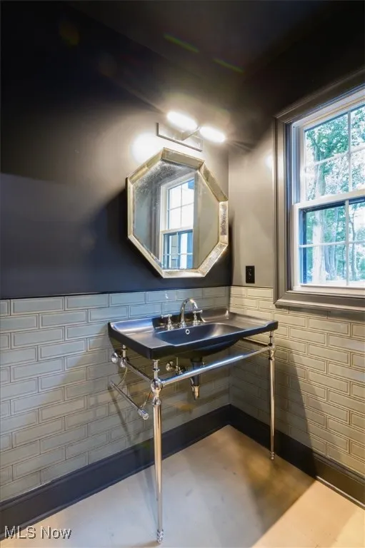 Bathroom with a wainscoted wall, healthy amount of natural light, and tile walls