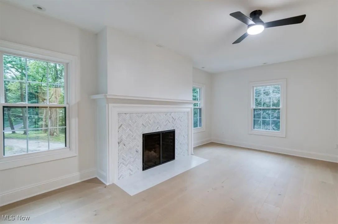 Bedroom featuring a tiled fireplace, light wood-type flooring, and a ceiling fan