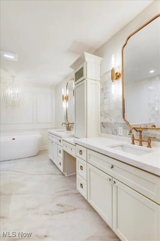 Bathroom featuring a soaking tub, two vanities, a chandelier, and decorative backsplash