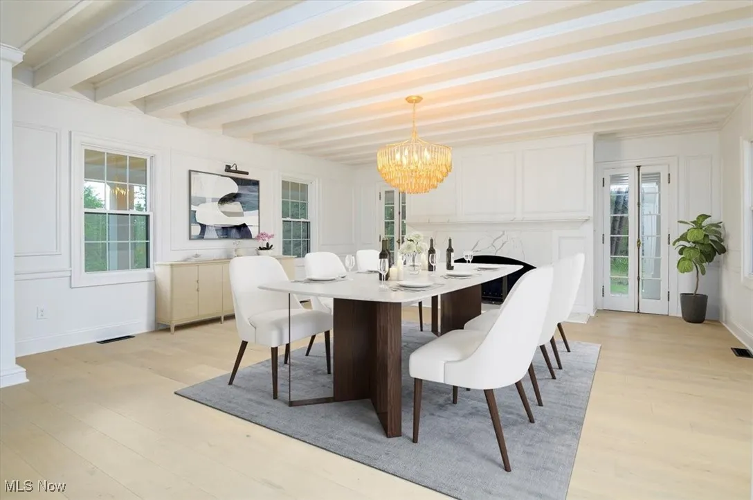 Dining space featuring a chandelier, light wood finished floors, and beamed ceiling