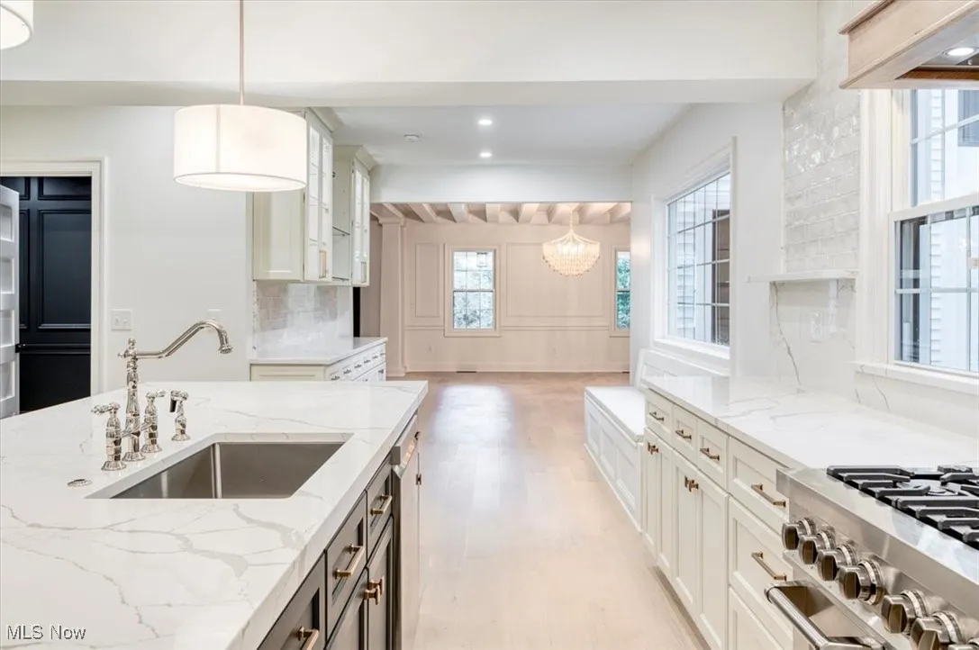 Kitchen with light stone counters, pendant lighting, backsplash, light wood finished floors, and recessed lighting