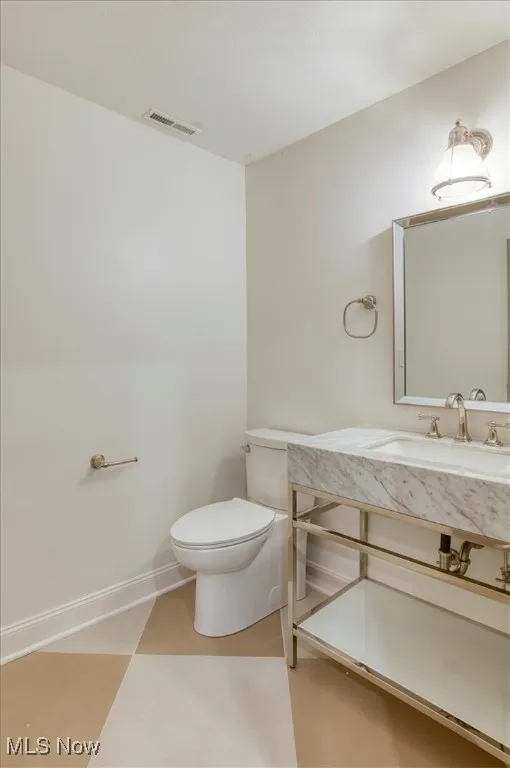 Half bathroom with toilet and vanity in mudroom/laundry