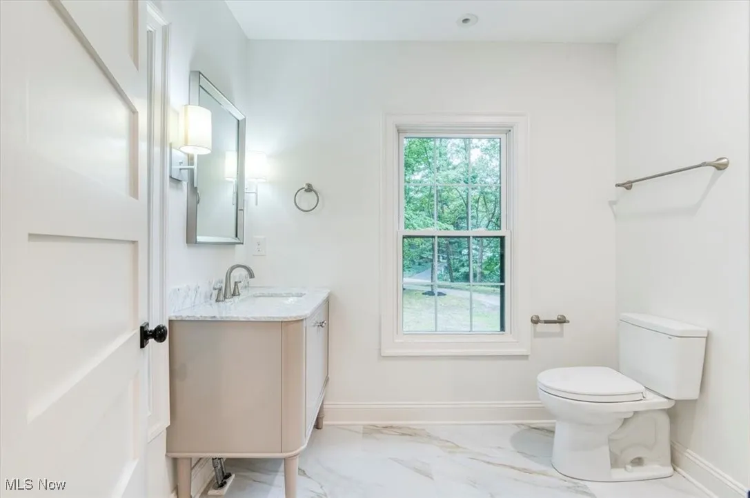 Half bathroom with light marble finish flooring and vanity