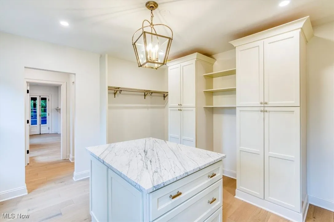 Spacious closet featuring light wood-style floors and a chandelier