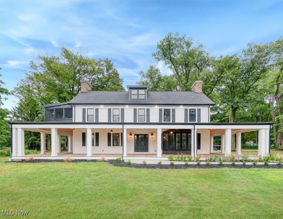 View of front of house featuring a chimney, covered porch, and a front lawn