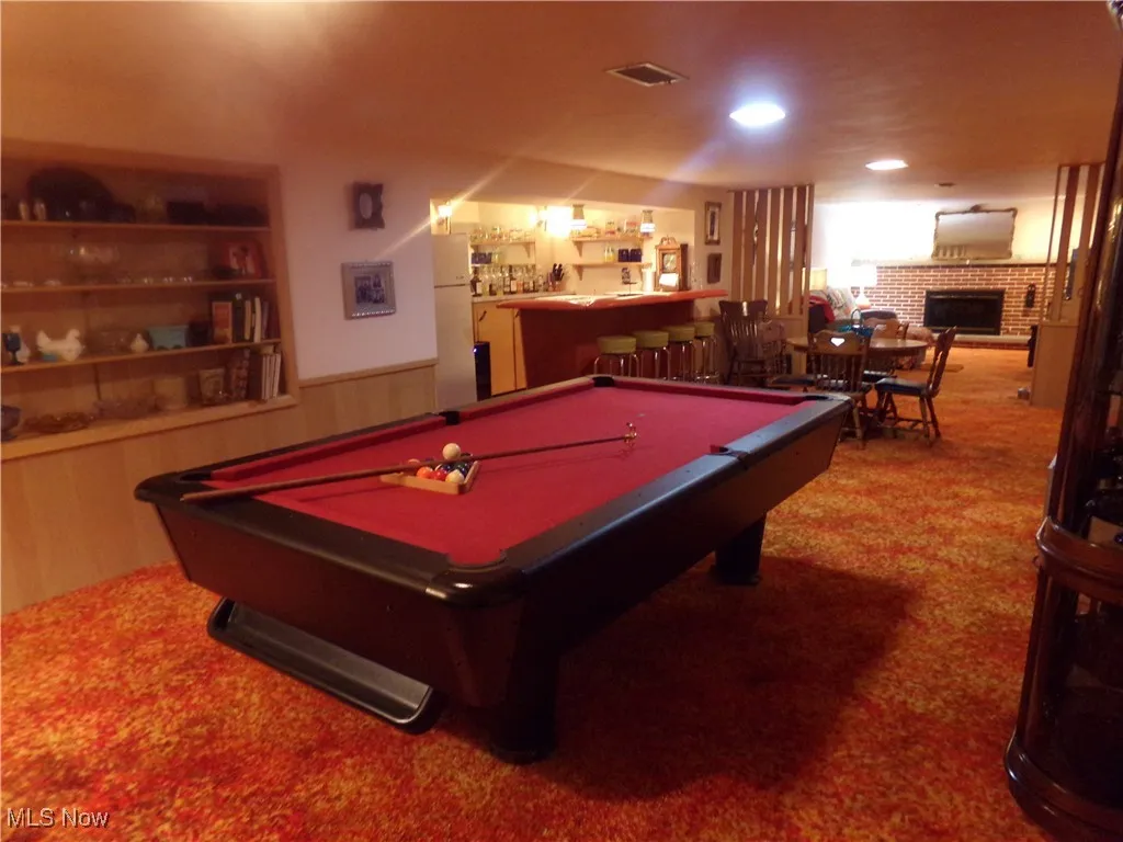 Playroom featuring a fireplace, carpet flooring, bar, a wainscoted wall, and pool table