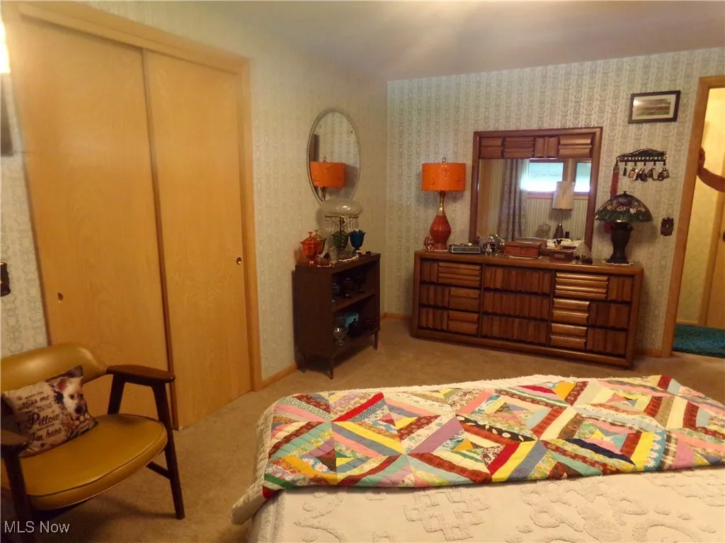 Bedroom featuring light colored carpet and wallpapered walls