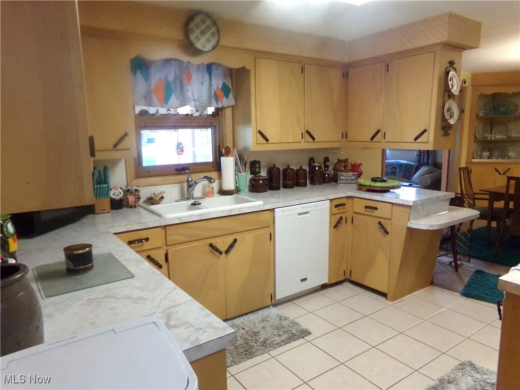 Kitchen featuring light countertops, light tile patterned flooring, and white dishwasher