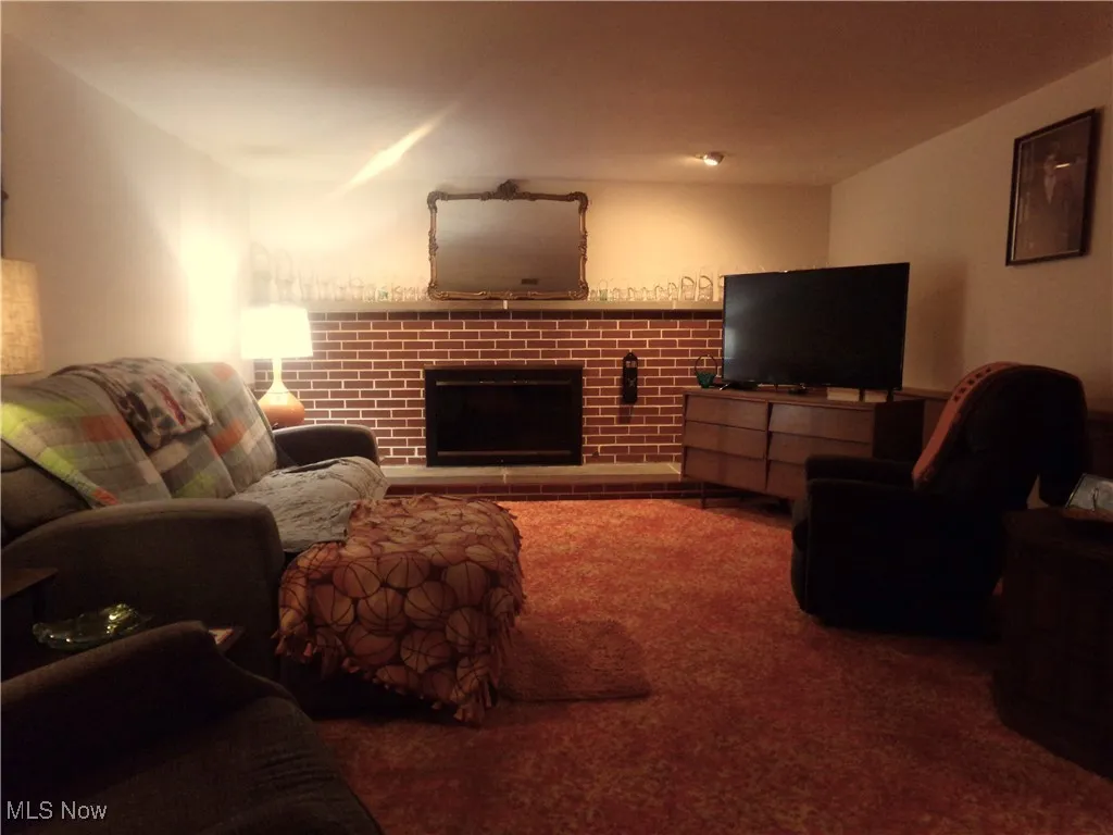 Carpeted living area featuring a brick fireplace
