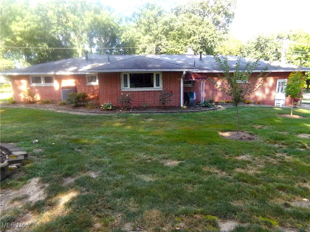 Back of house featuring a lawn and brick siding