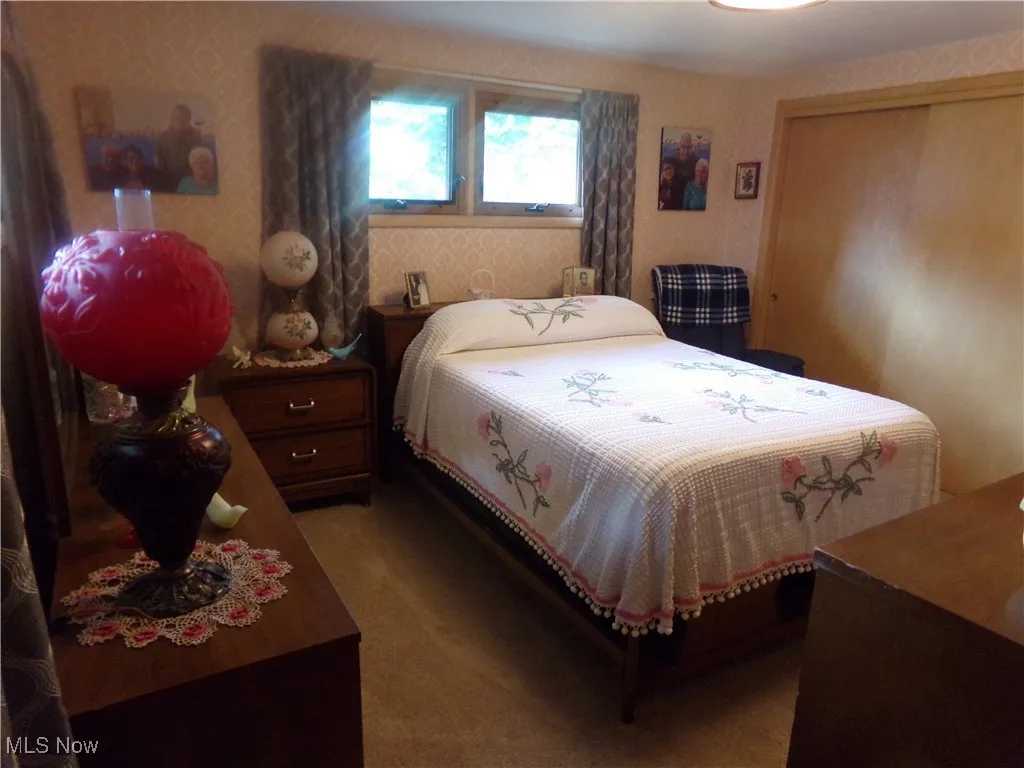 Carpeted bedroom featuring wallpapered walls and a closet