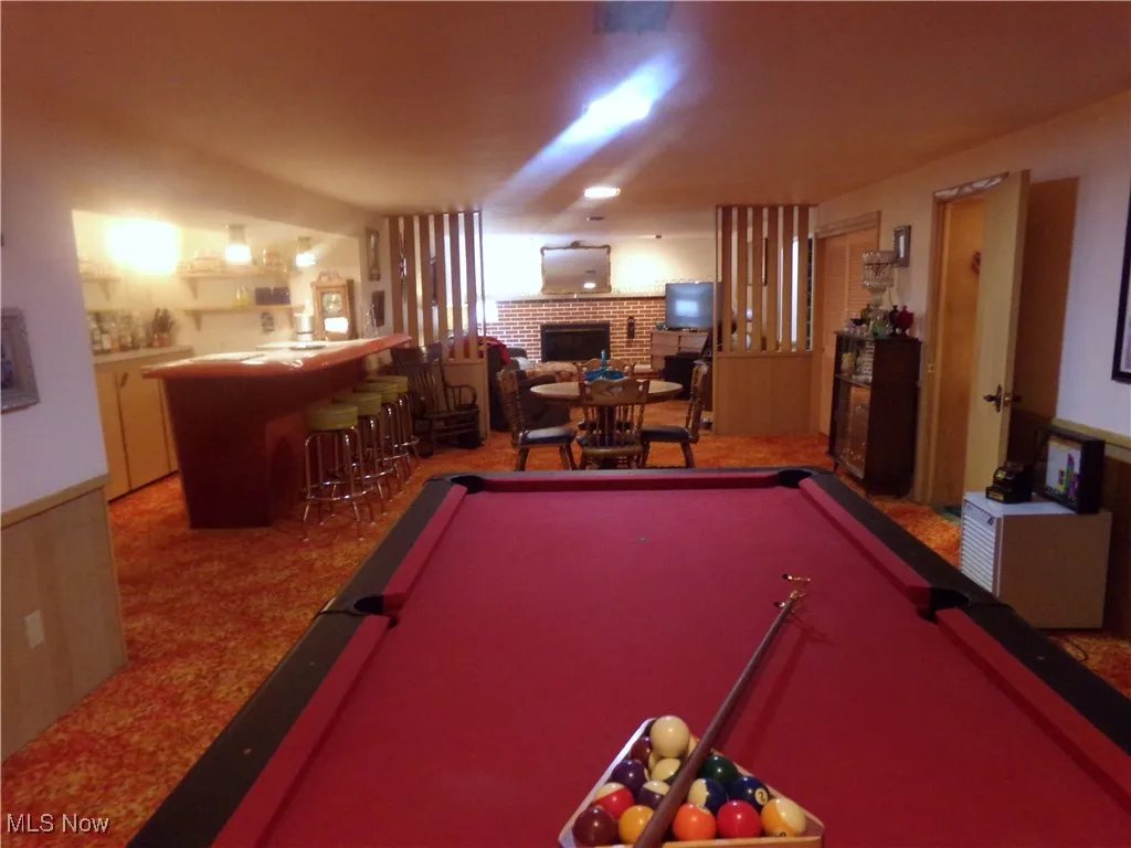 Playroom featuring a fireplace, light carpet, pool table, and bar area