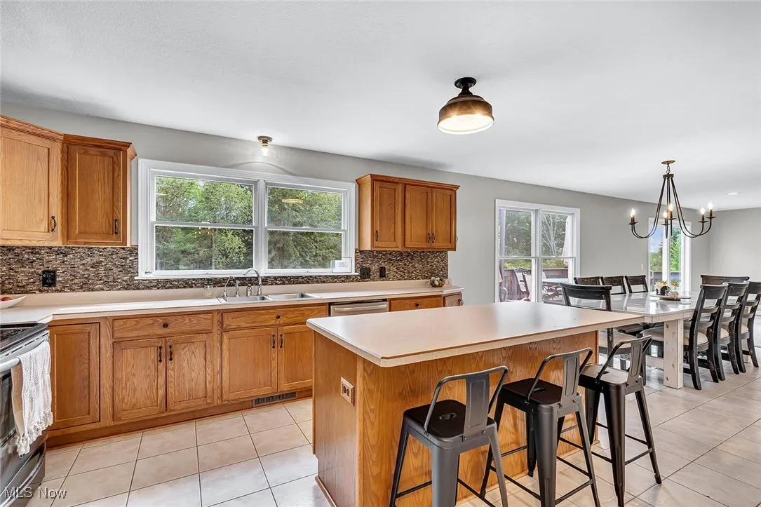 Kitchen with a breakfast bar, brown cabinets, light tile patterned floors, light countertops, and a chandelier