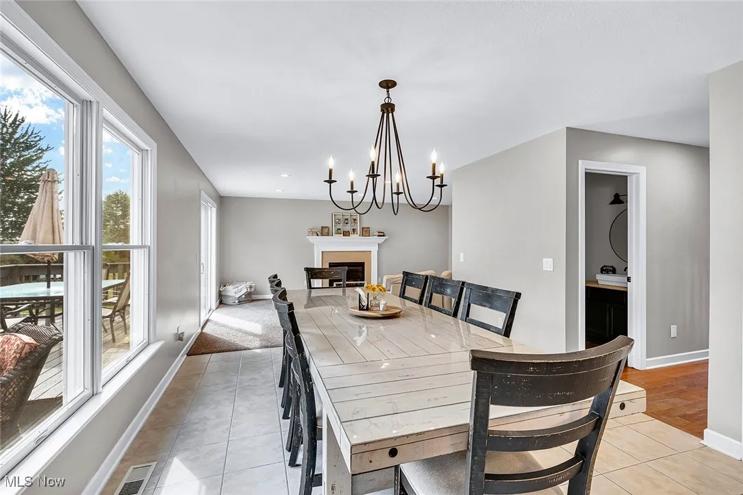 Dining space with light tile patterned flooring, a fireplace, and a chandelier