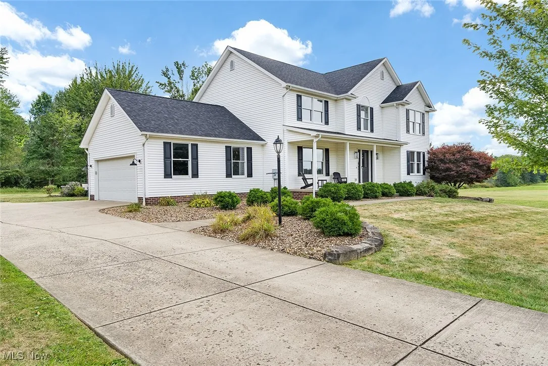 View of front of property featuring a front lawn, a shingled roof, an attached garage, driveway, and a porch