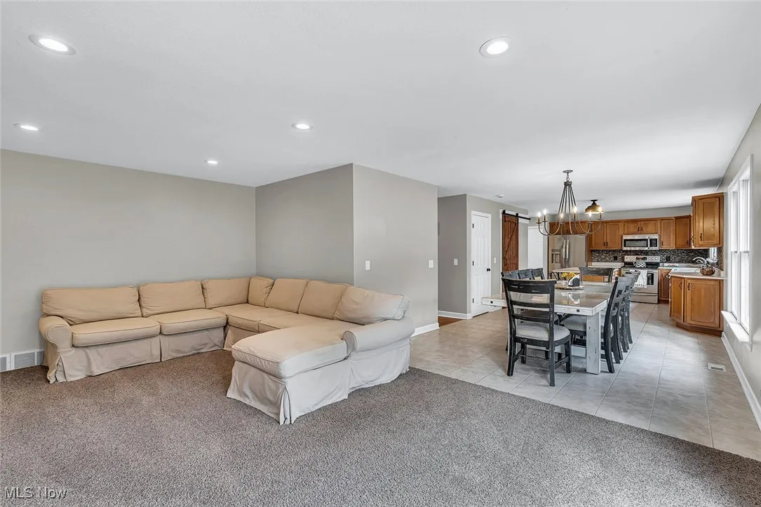 Living room featuring light tile patterned flooring, light carpet, a chandelier, and recessed lighting