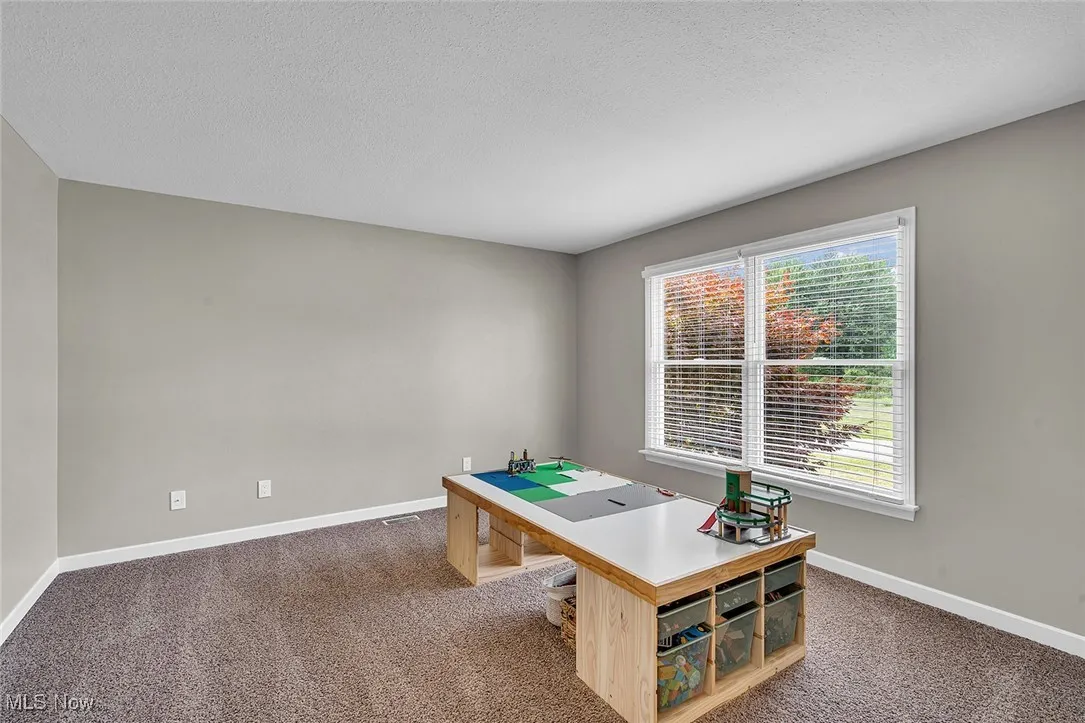 Office space featuring dark colored carpet and a textured ceiling