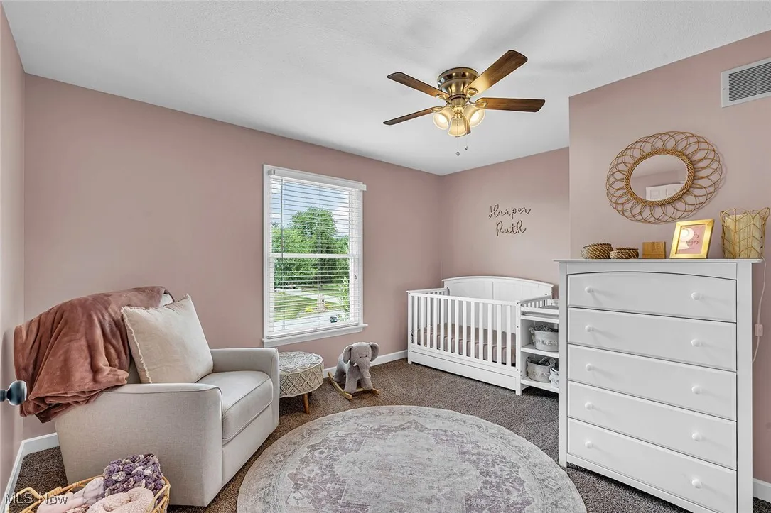 Bedroom featuring carpet floors, ceiling fan, and a nursery area
