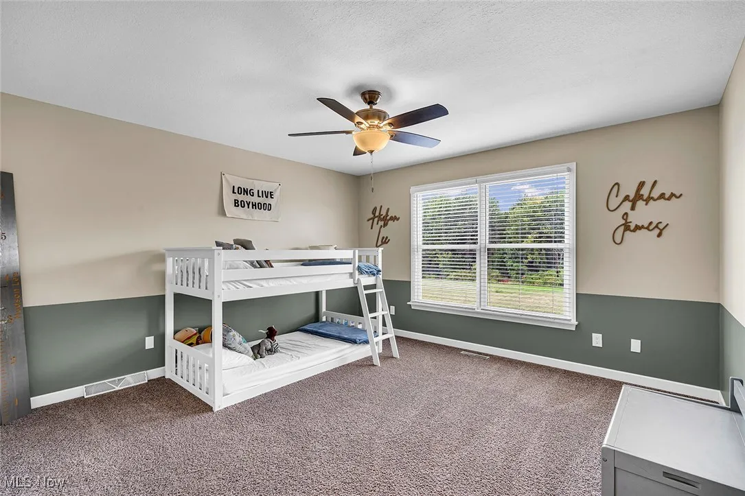 Bedroom featuring carpet floors, ceiling fan, and a textured ceiling