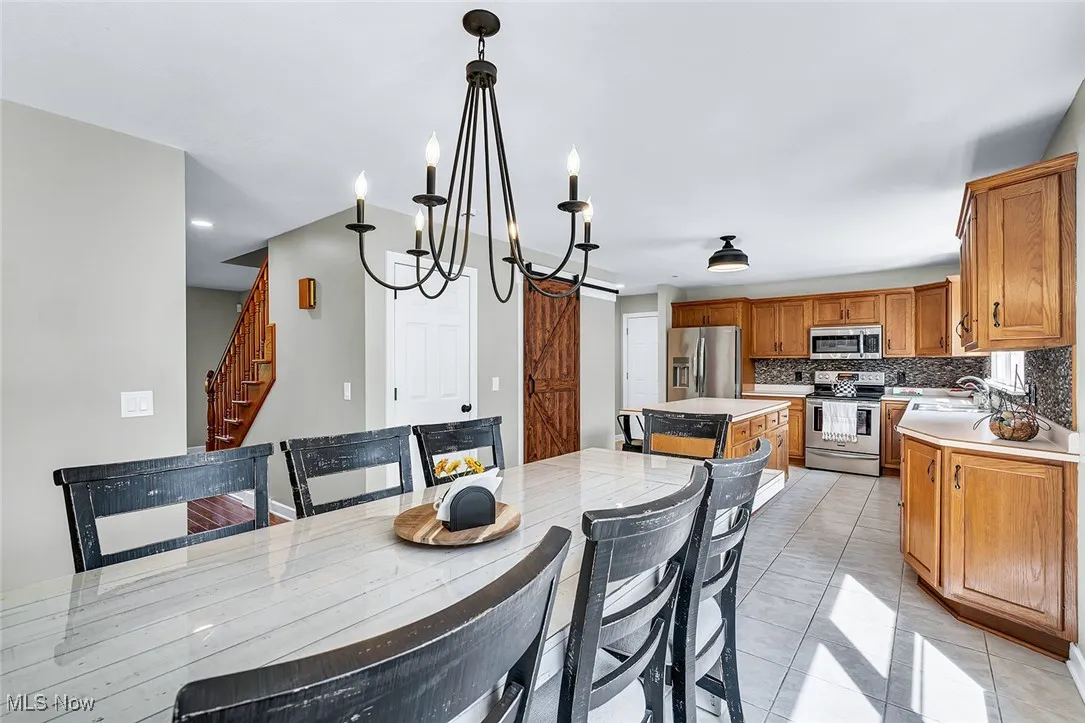 Dining space featuring stairs, light tile patterned floors, and a chandelier