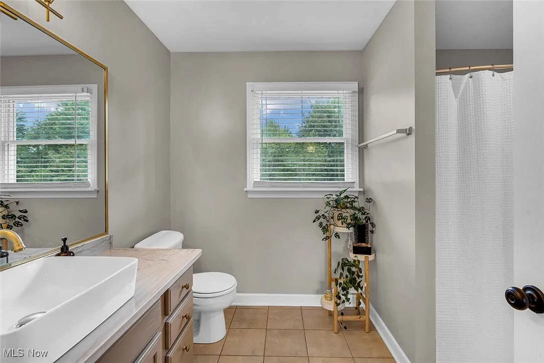 Full bathroom featuring light tile patterned flooring, vanity, healthy amount of natural light, and a shower with curtain