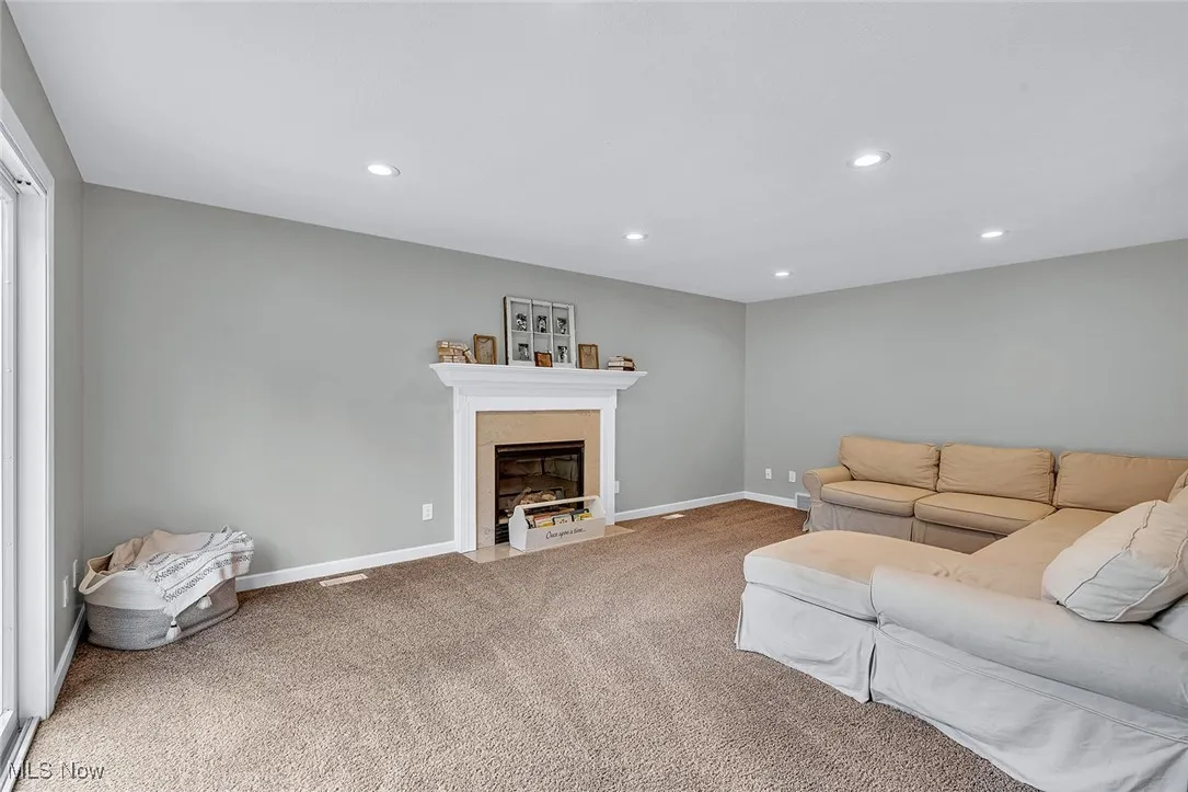 Living area featuring recessed lighting, a fireplace with flush hearth, and light colored carpet