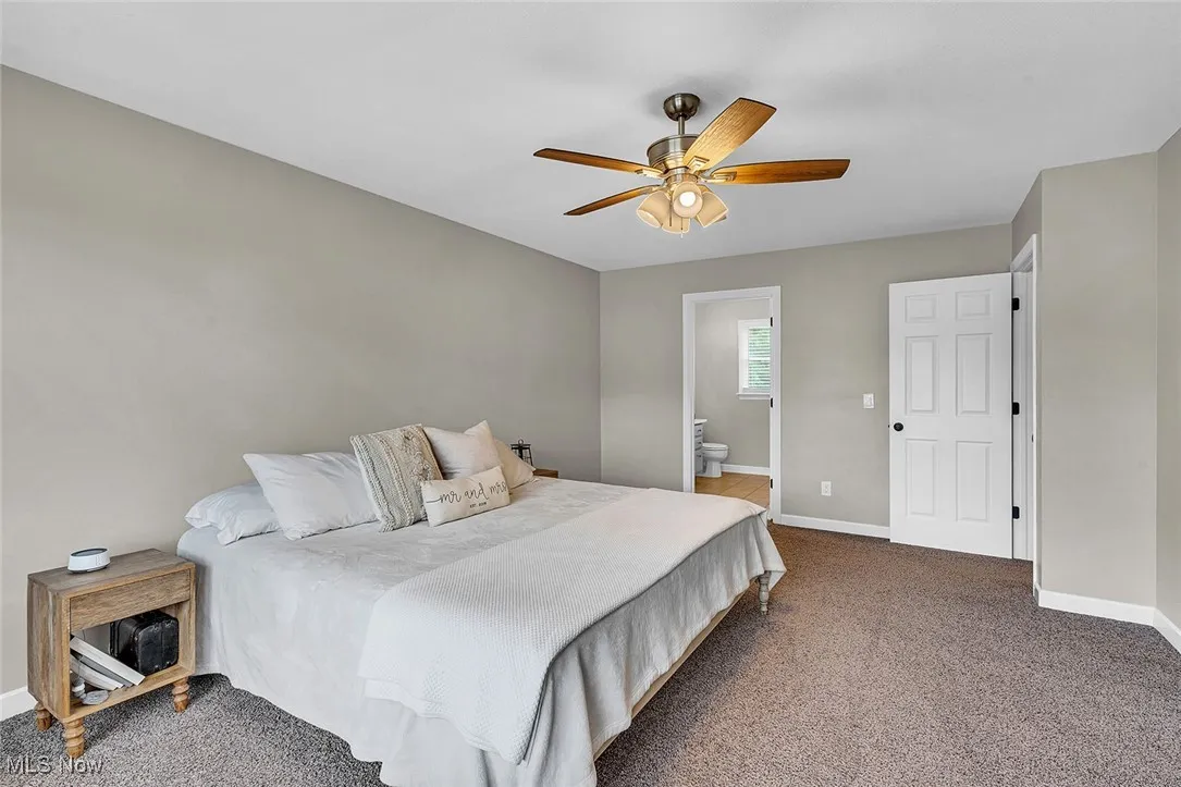 Bedroom with carpet flooring, ceiling fan, and connected bathroom