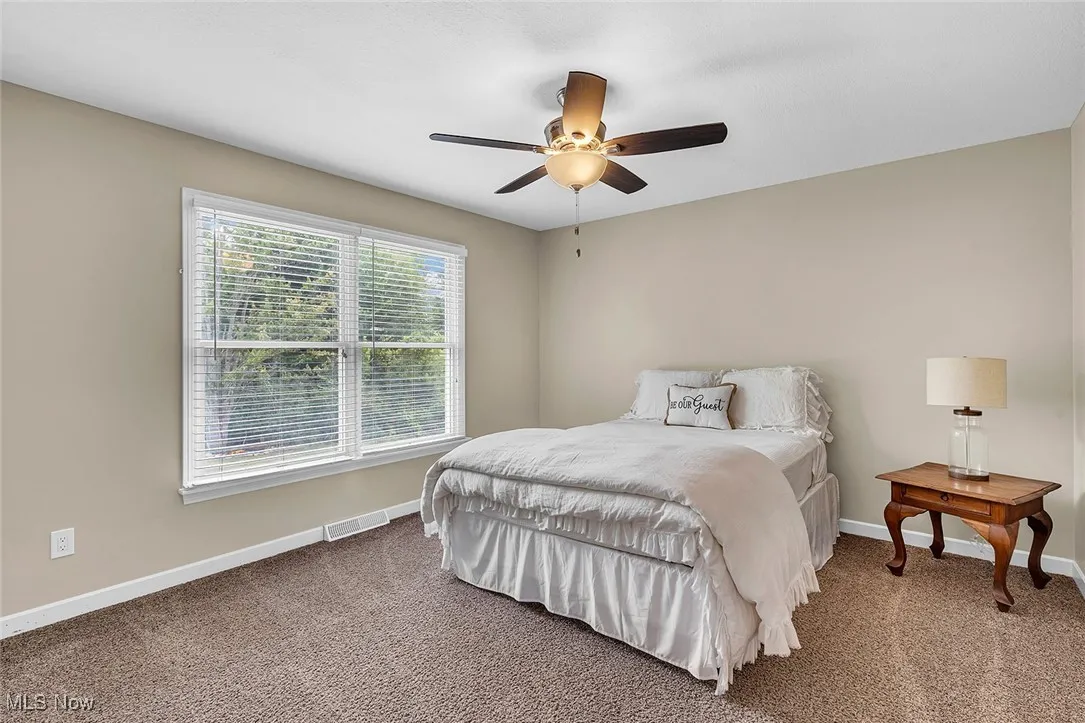 Carpeted bedroom featuring a ceiling fan and baseboards