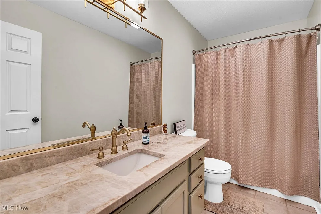 Full bath with vanity, light tile patterned floors, and a shower with curtain