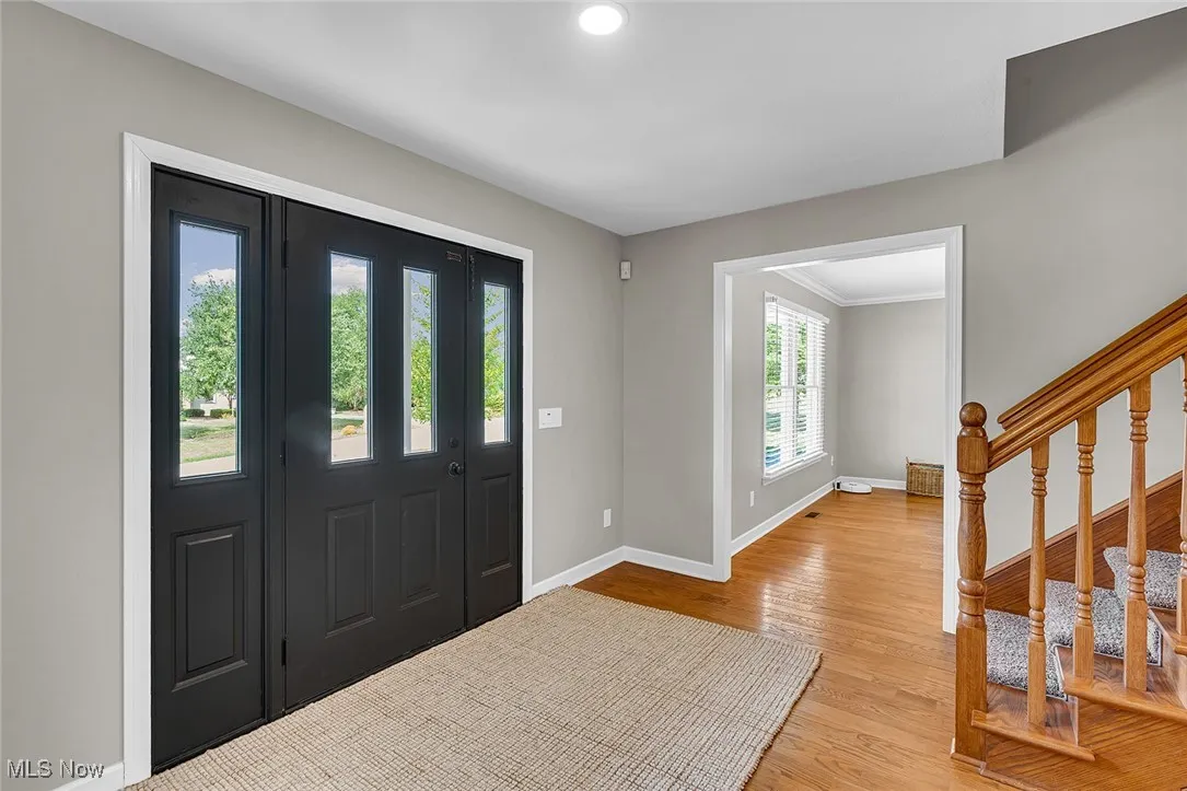 Entrance foyer featuring stairway, light wood-style flooring, and ornamental molding
