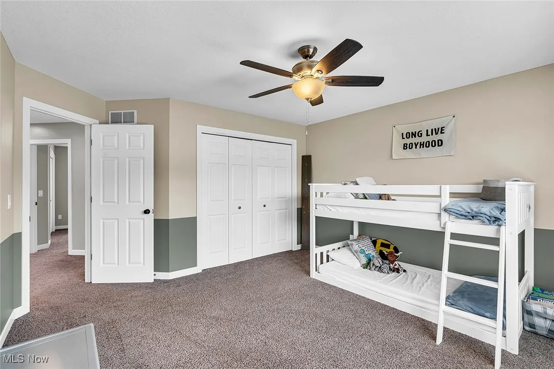 Carpeted bedroom with a closet and ceiling fan