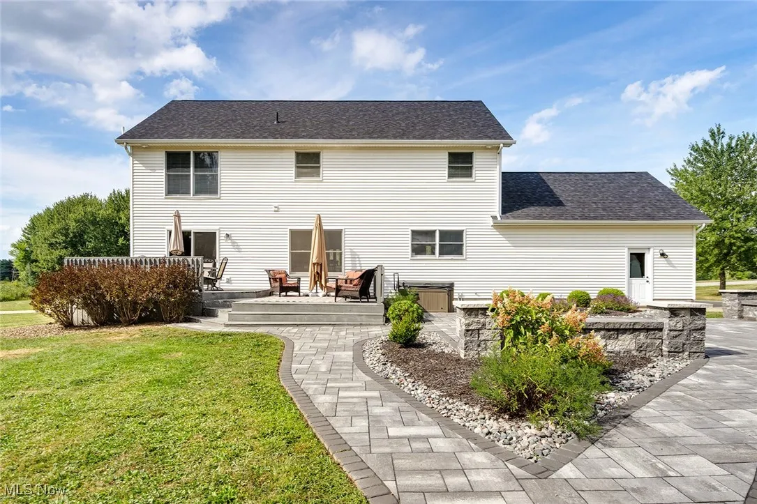 Back of house featuring a yard, a deck, and roof with shingles