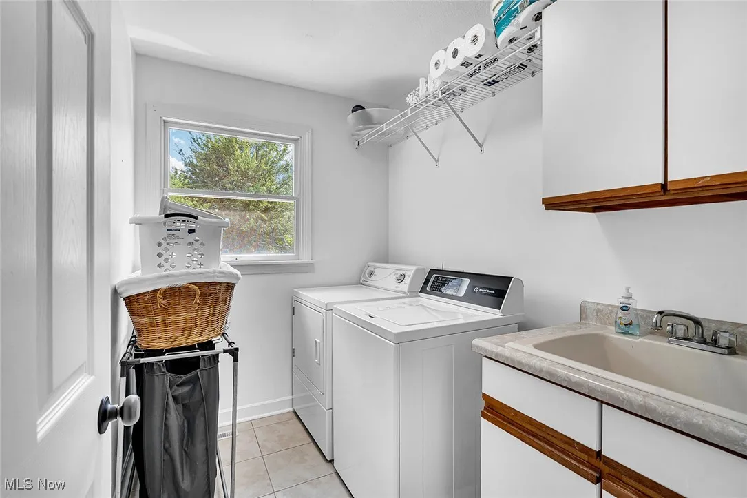Washroom featuring light tile patterned floors, cabinet space, and washer and clothes dryer