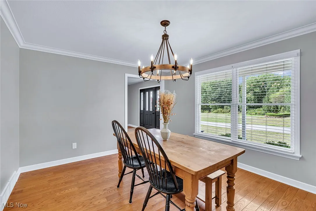 Dining area with crown molding, light wood-style flooring, and a chandelier