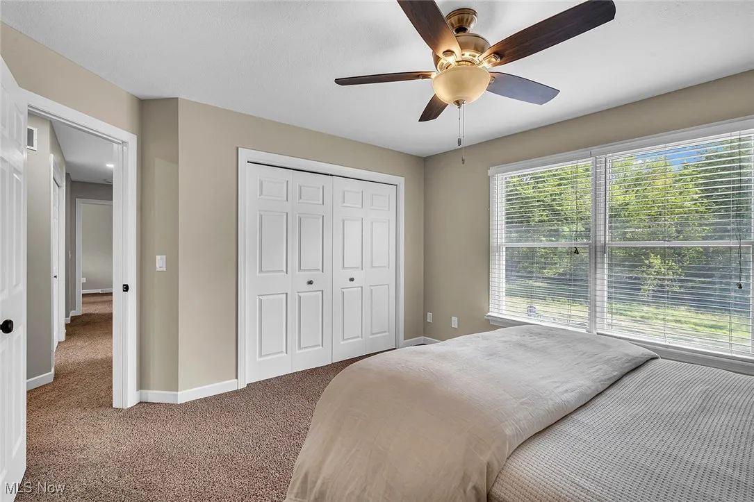 Carpeted bedroom with a closet and ceiling fan