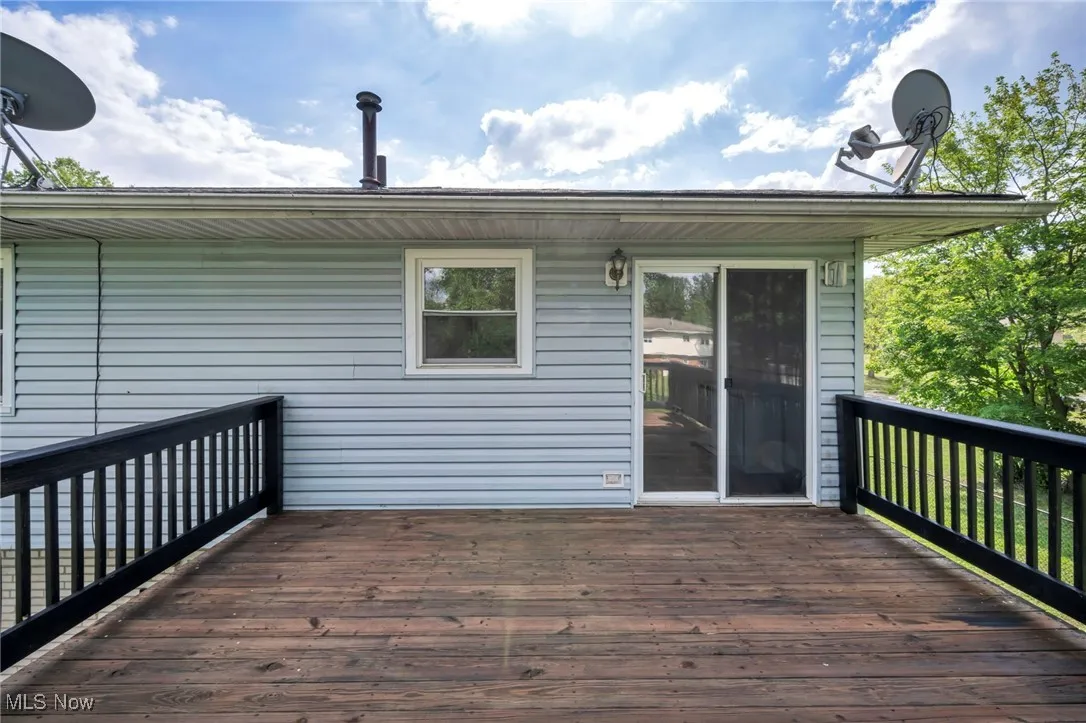 Freshly stained and painted wooden terrace overlooking view of fenced-in backyard and trees