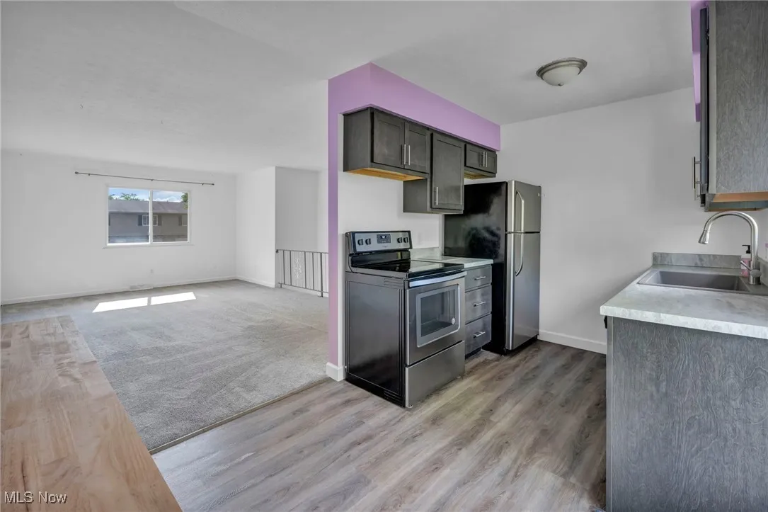 Eat-in Kitchen with light countertops, stainless steel appliances, light wood-style flooring, and access to private deck