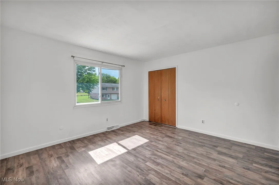 Bedroom with dark wood-type flooring and baseboards