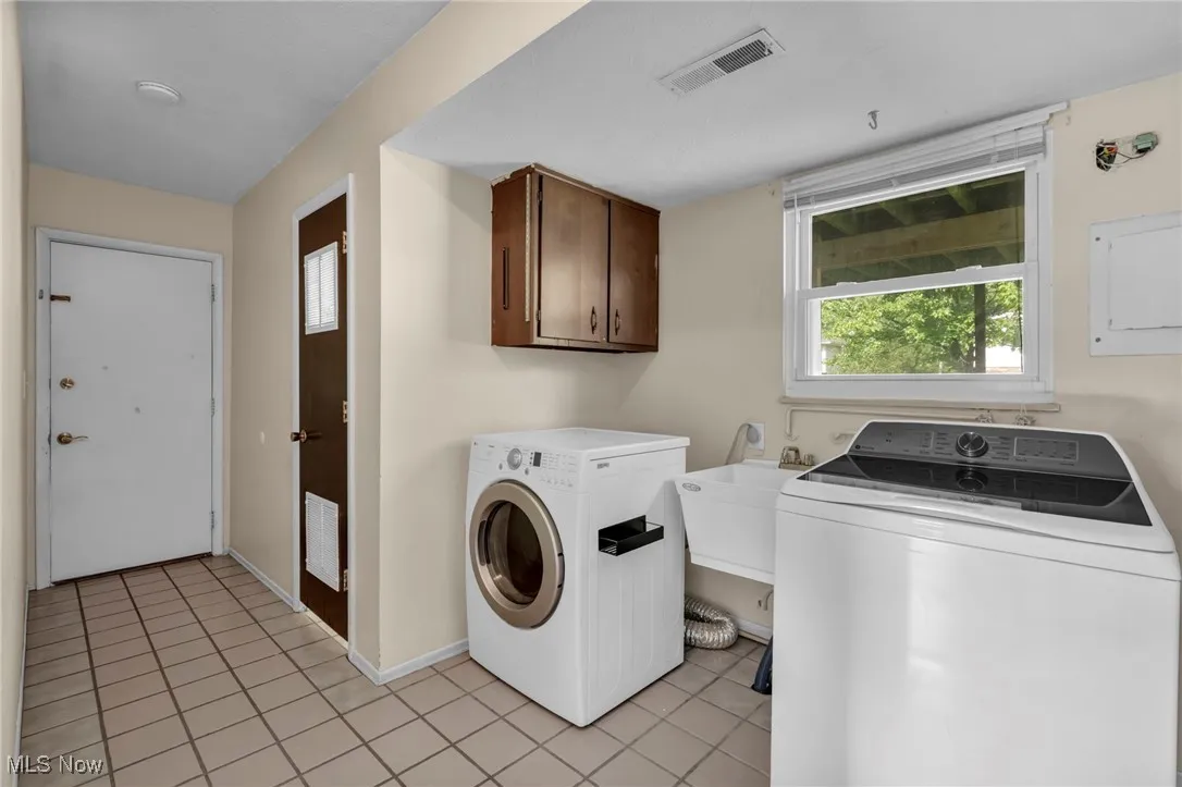 Laundry room featuring washing machine and dryer, plenty of natural light, light tile patterned floors