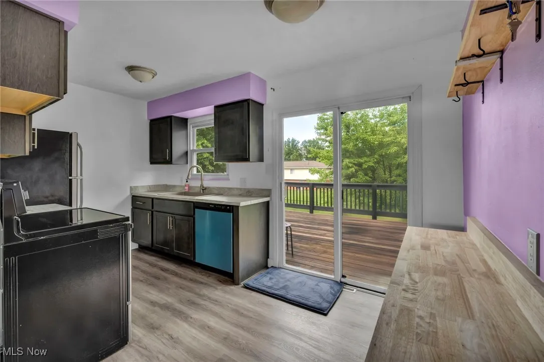 Eat-in Kitchen with light countertops, stainless steel appliances, light wood-style flooring, and access to private deck