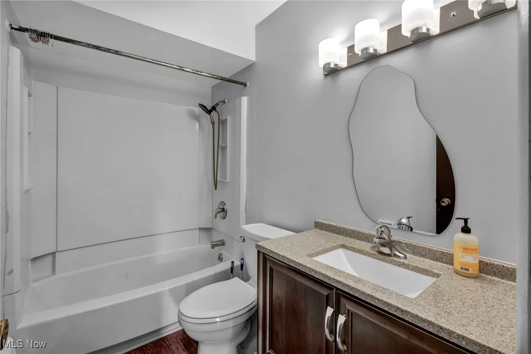 Updated bath featuring shower/bathtub combination, vanity, and dark wood-type flooring