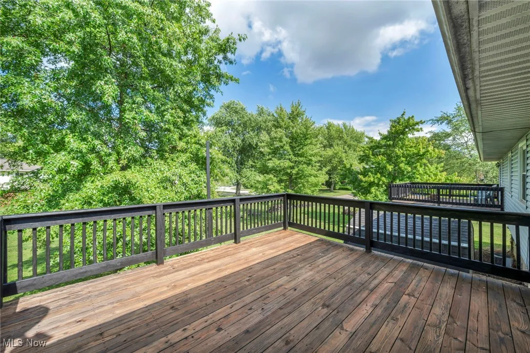 Freshly stained and painted wooden terrace overlooking view of fenced-in backyard and trees
