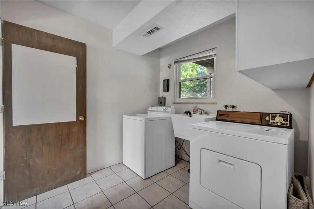 Laundry room with washing machine and clothes dryer, light tile patterned flooring, and cabinet space