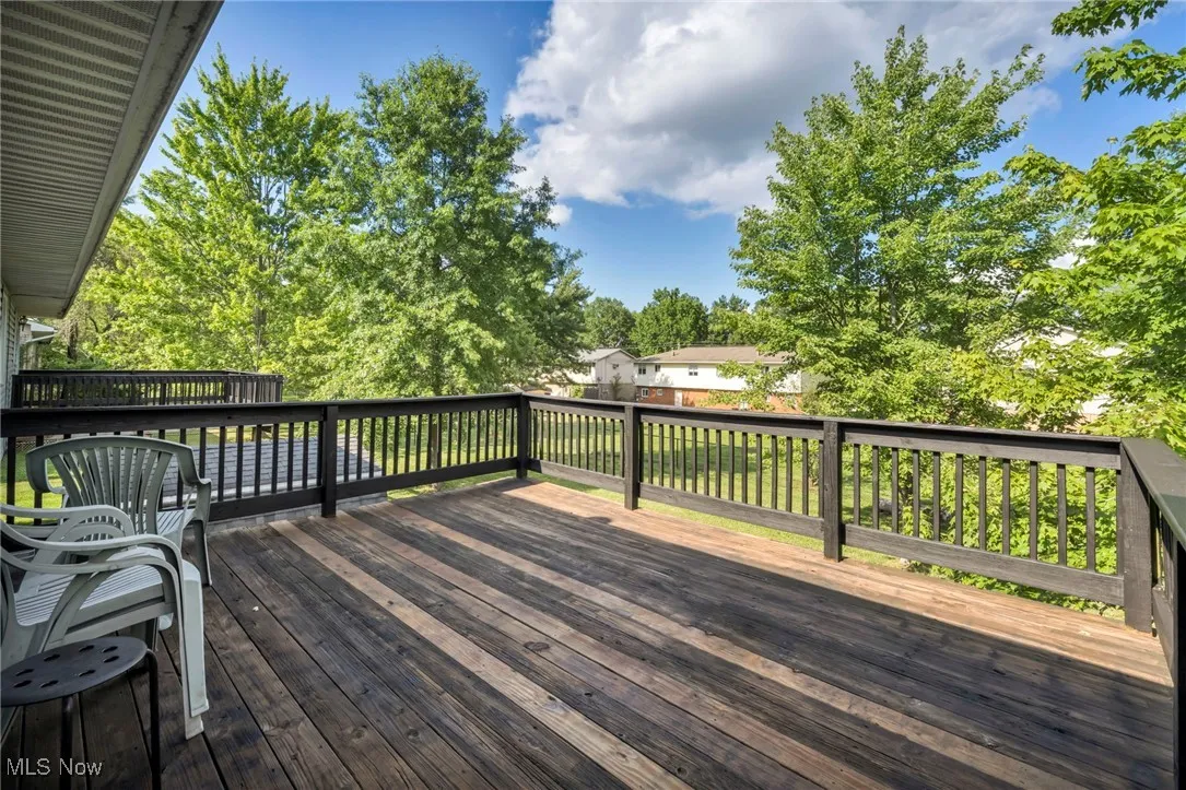 Freshly stained and painted wooden terrace overlooking view of fenced-in backyard and trees