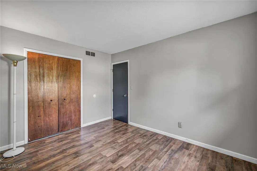 Bedroom with dark wood-type flooring and baseboards